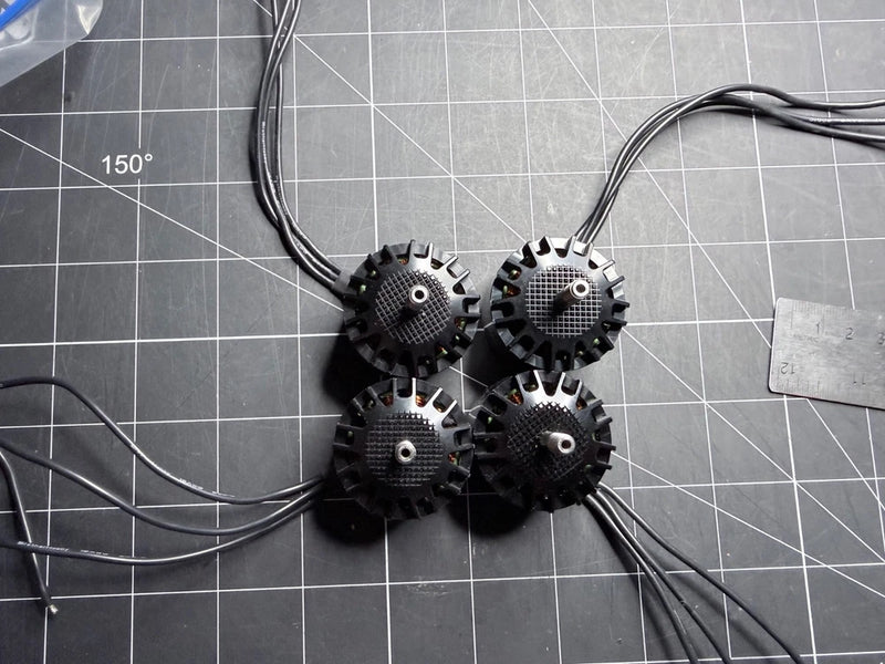 Set of four FPV drone motors with black housings and attached wire leads