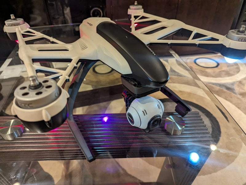 White and black quadcopter drone with blue LEDs and landing gear