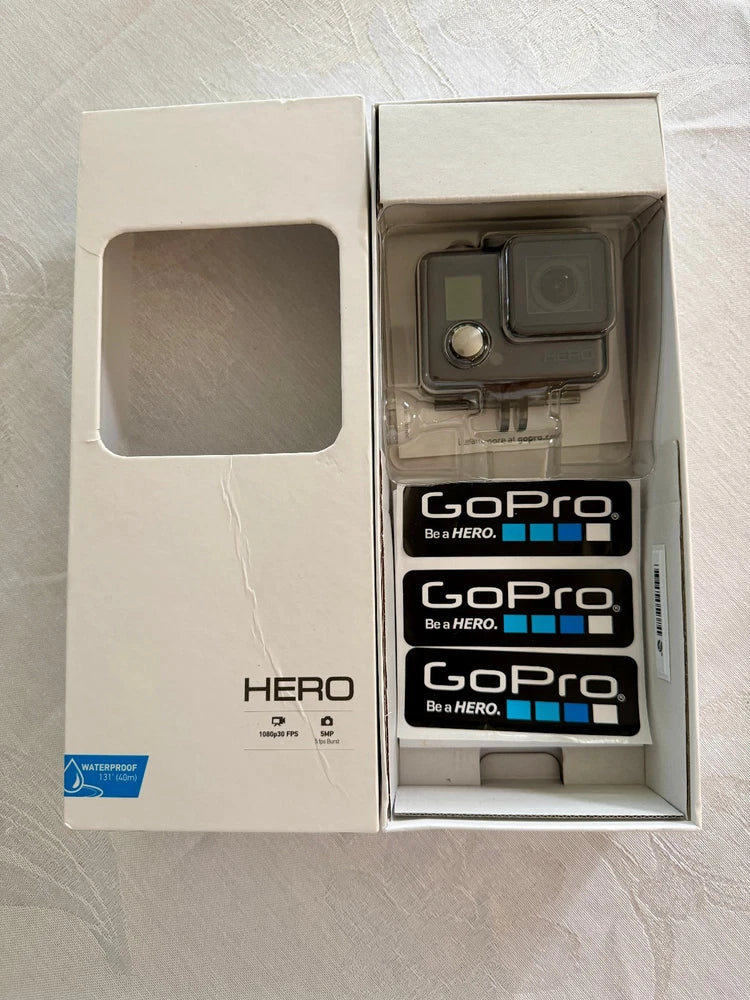 GoPro HERO+ waterproof action camera in open box with mounted housing and stickers