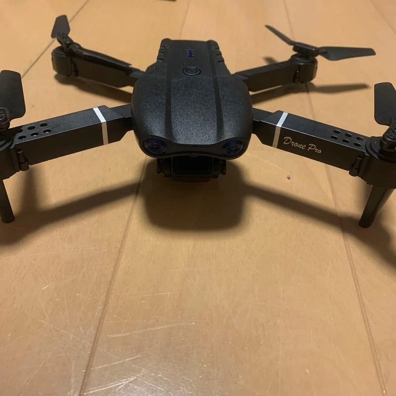 Black quadcopter drone with front camera, four propellers, remote control toy