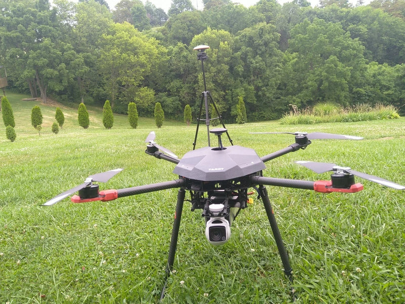 X4 heavy lift drone with red arms, landing legs, and front camera gimbal