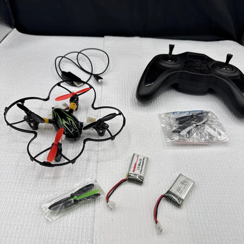 Small quadcopter drone with controller, spare parts, and cables laid out for parts repair