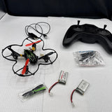 Small quadcopter drone with controller, spare parts, and cables laid out for parts repair