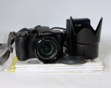 Black Panasonic Lumix digital camera with lens, strap, and lens hood accessory