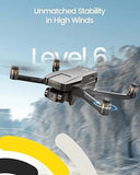 Gray quadcopter drone with camera and propellers, angled view in flight