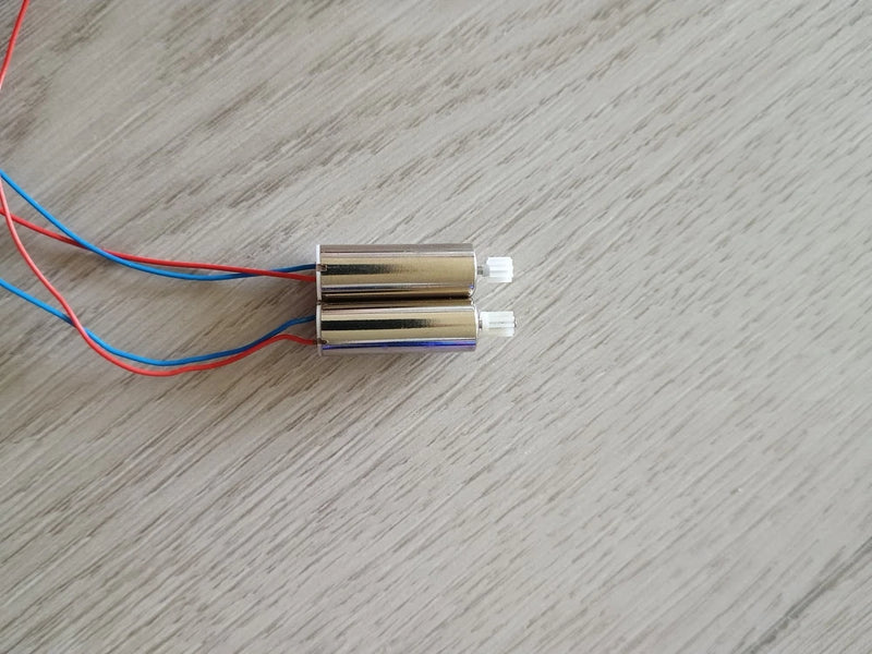 Pair of drone motors with blue and red wiring and white electrical connectors