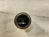 Round analog battery charge gauge with black face, red scale, white pointer, metal bezel