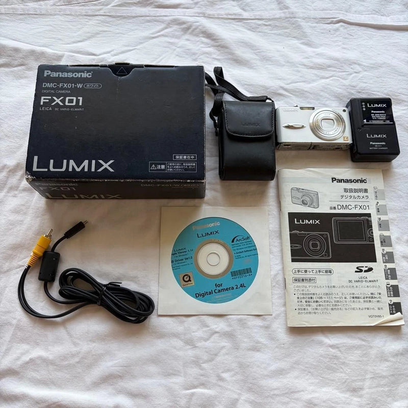 White Panasonic Lumix compact digital camera with lens, black case, manuals, disc, cables