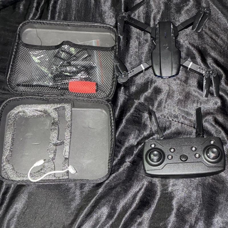 Foldable quadcopter drone with remote controller and gray carry case, shown with open compartment