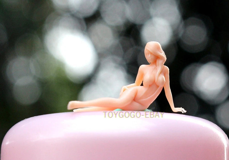 Seated female miniature figure posed on pink car hood
