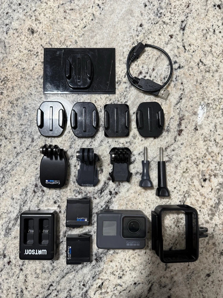 Black action camera with accessories and mounts, including waterproof case and straps
