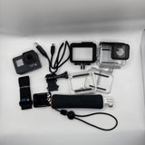 Black action camera bundle with clear waterproof housings, mounts, and straps