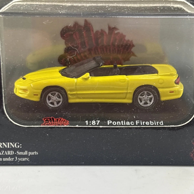 Yellow 1:87 Pontiac Firebird die-cast car in clear blister packaging