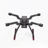 Quadcopter drone frame with four arms, central controller plate, and red antennas