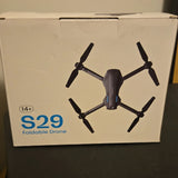 Foldable quadcopter drone with camera and four black propellers on retail box