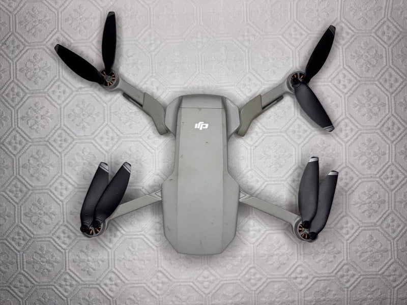 Compact drone with four folded propellers, light gray body and front camera pod