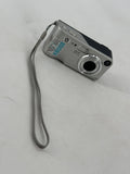 Silver compact digital camera with front lens and top buttons