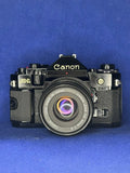 Canon A-1 film camera with attached FD 50mm lens, front view, black metal body