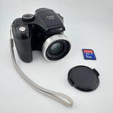 Black digital camera with zoom lens, wrist strap, lens cap, and SanDisk 1GB SD card