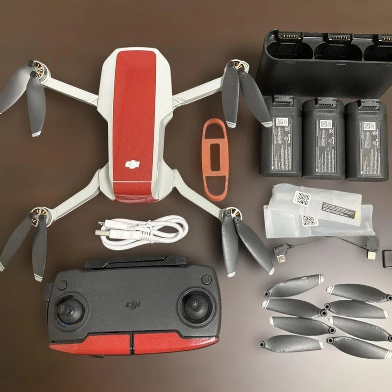 DJI quadcopter drone with red-and-white body, controller, batteries, propellers, cables