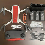 DJI quadcopter drone with red-and-white body, controller, batteries, propellers, cables