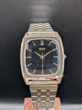 Gold-tone rectangular SEIKO Quartz wristwatch with black dial, Roman numerals, metal bracelet