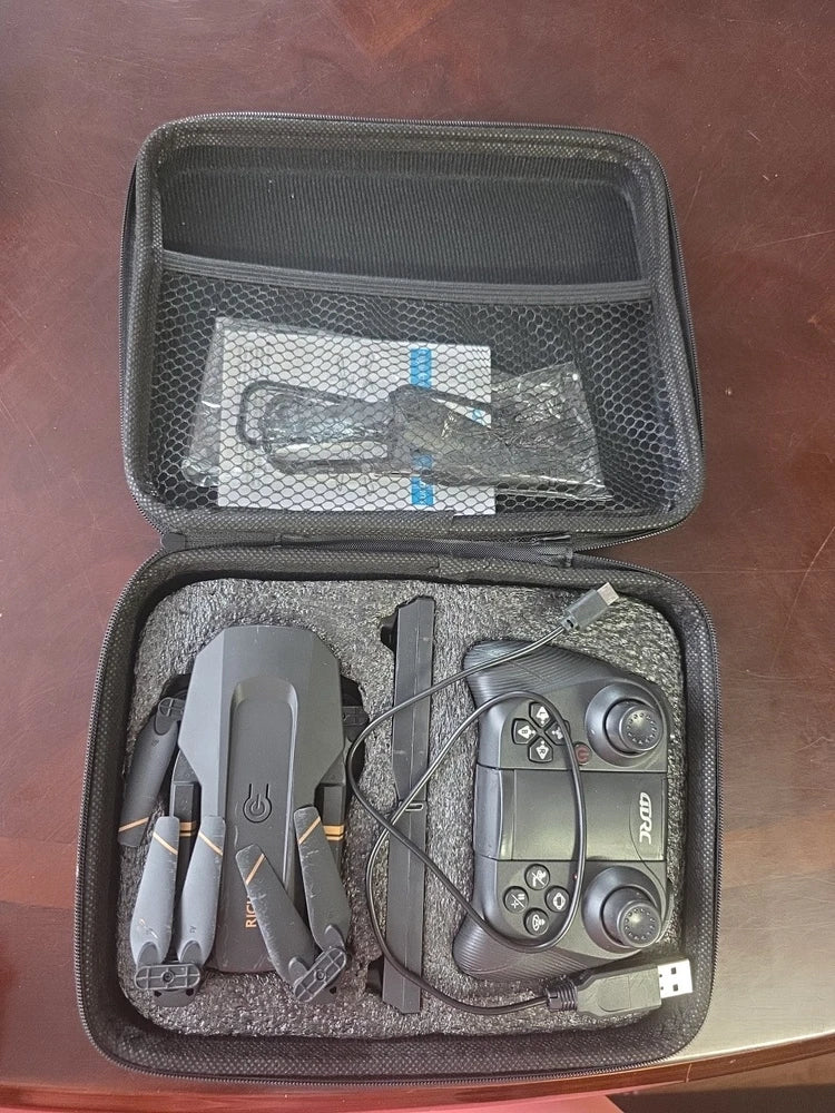 Foldable quadcopter drone with controller in open hard carry case and charging cables
