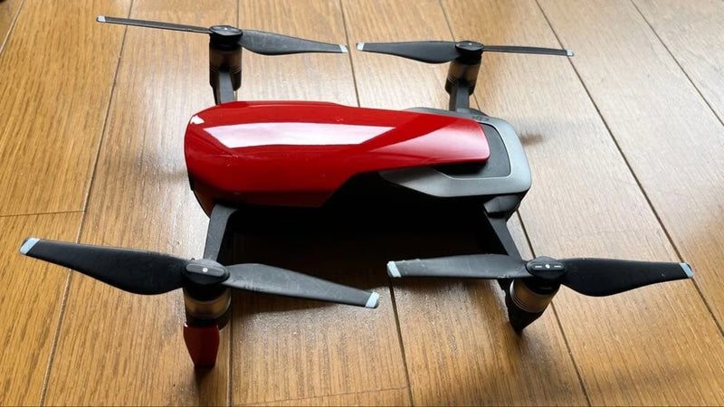 Used red and gray quadcopter drone with four propellers, body and landing gear visible