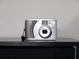 Silver digital camera with front lens and HP logo, 3.2MP badge on top right