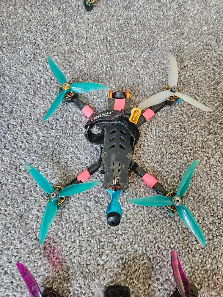 Teal and black FPV quadcopter drone with four propellers and colorful arm covers