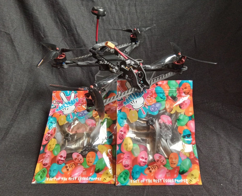 FPV racing drone with four propellers, shown with two colorful spare blade packs