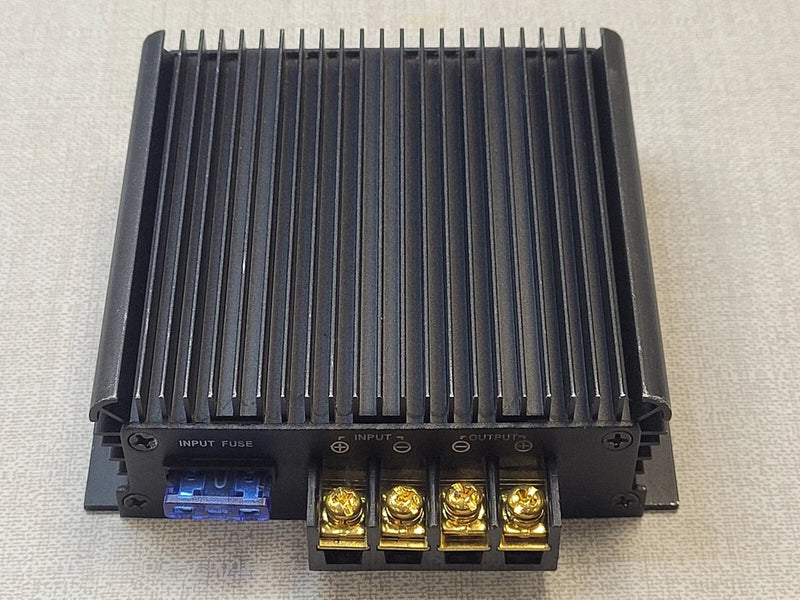 DC-DC converter with finned heatsink and screw terminal blocks, dark metal enclosure