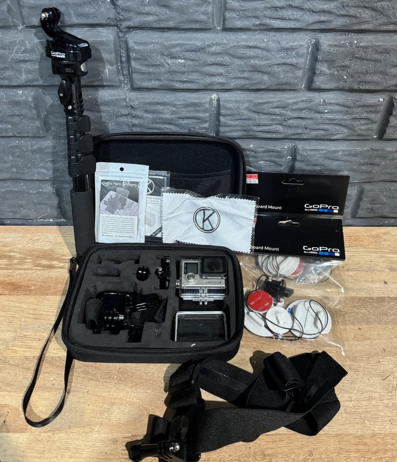 Action camera kit in open black case with camera, mounts, straps, cables, and papers