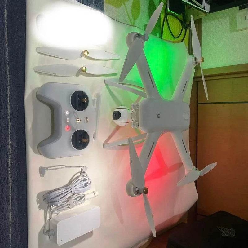 Gray quadcopter drone with four propellers, plus controller and cables—repair parts set.
