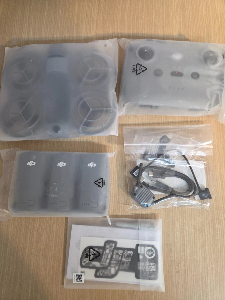 Refurbished drone accessory kit with controller, batteries, cables, and manuals in bags