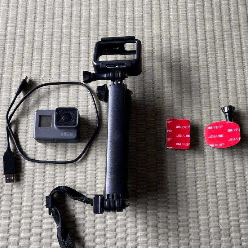GoPro HERO5 action camera body with black handle mount and red adhesive mounts