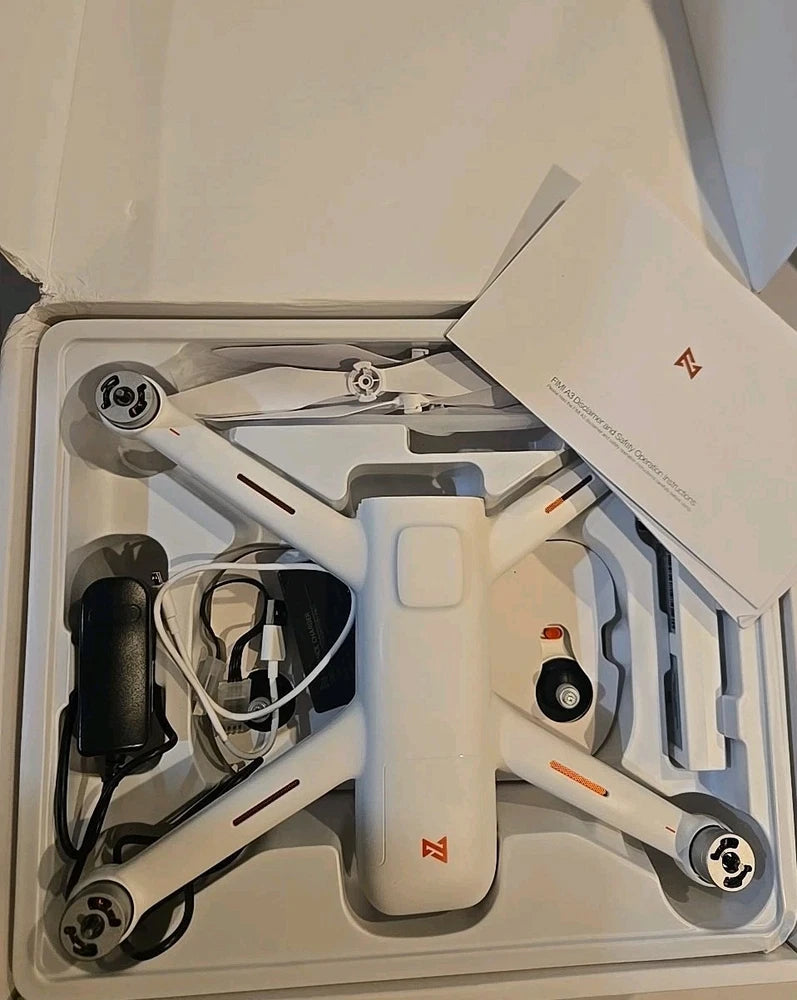 White HD drone with propellers in open kit box; charger and cables visible