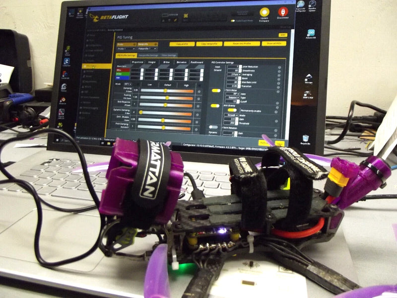 Purple FPV drone with quad frame, motors, and mounted prop guards on a desk