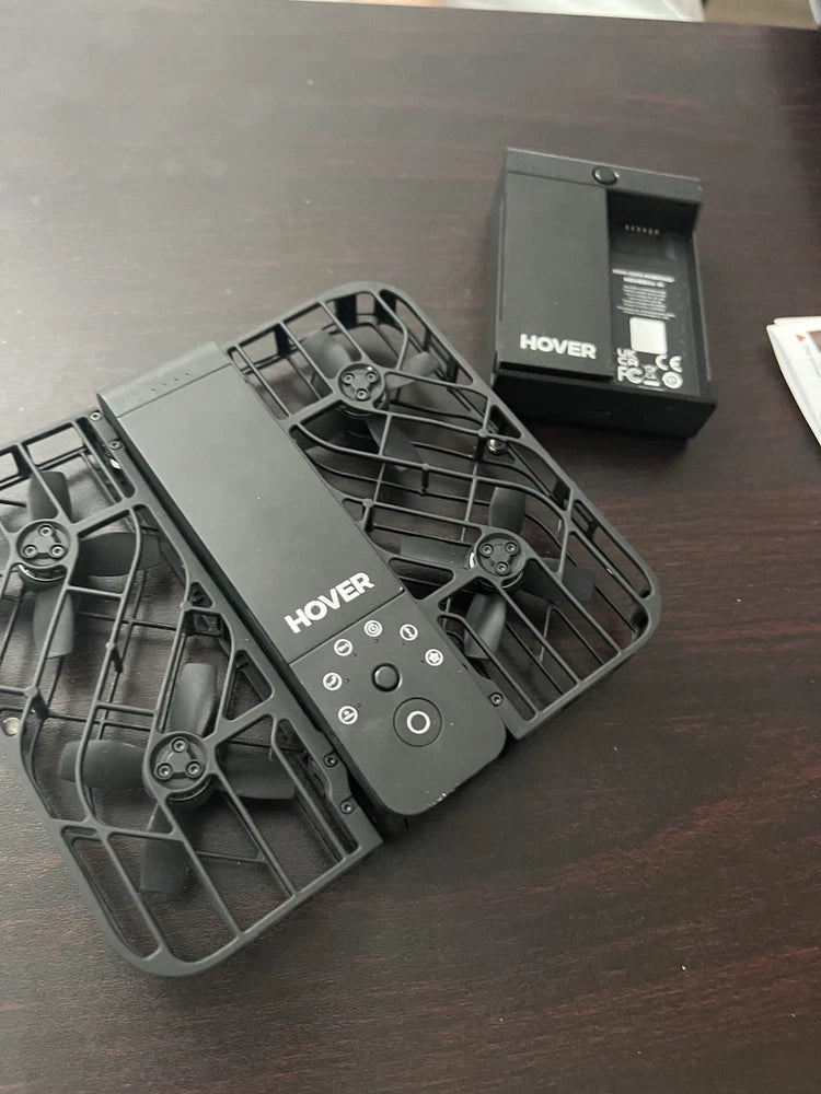 Folded compact drone with protective prop guards, central body visible