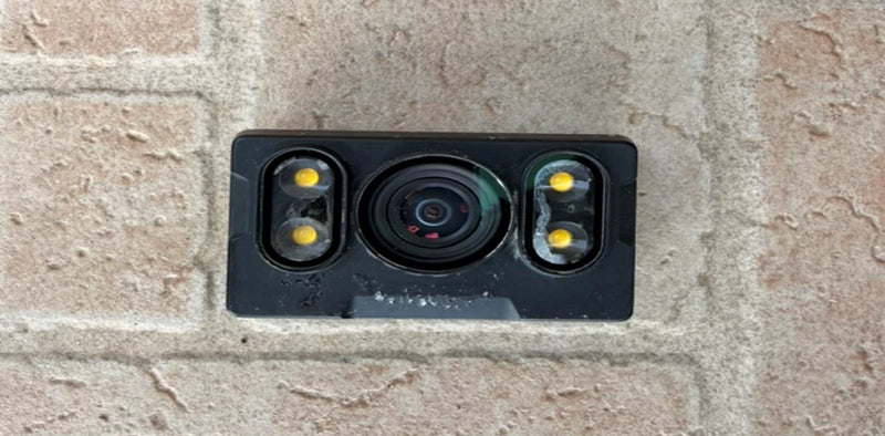 Rectangular FPV camera module with central lens and two built-in LED lights.