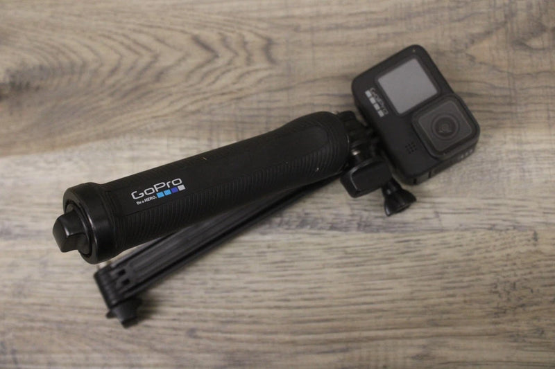 GoPro HERO9 Black action camera mounted on black selfie stick, front LCD visible
