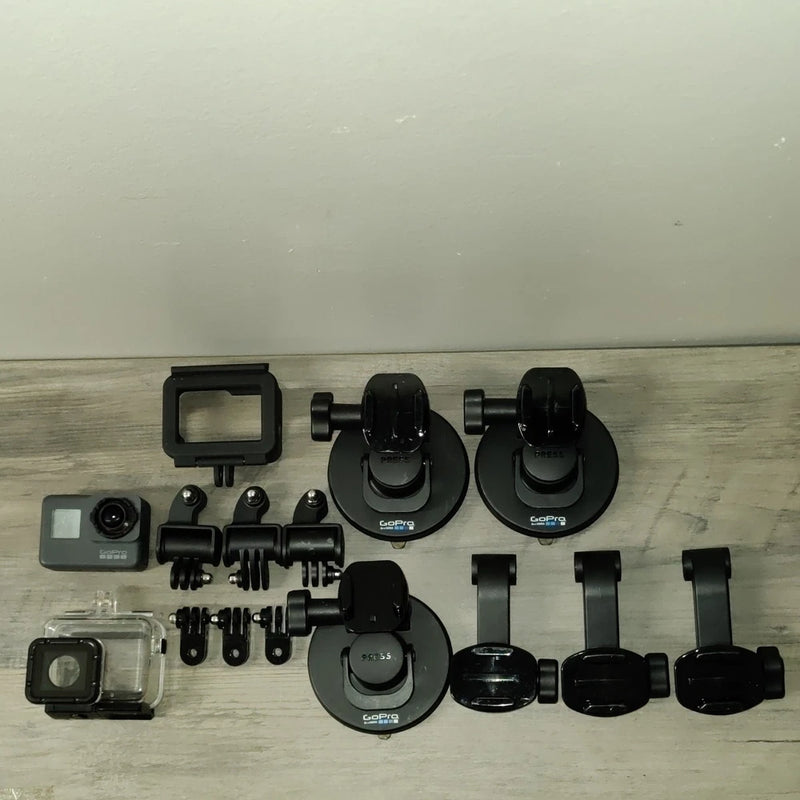 Gray action camera housing with mounts and accessories set for parts, including screen case and base clips