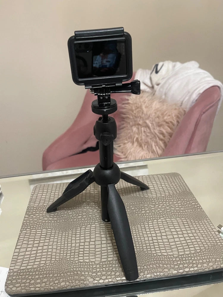 Black action camera in protective housing mounted on a small tripod