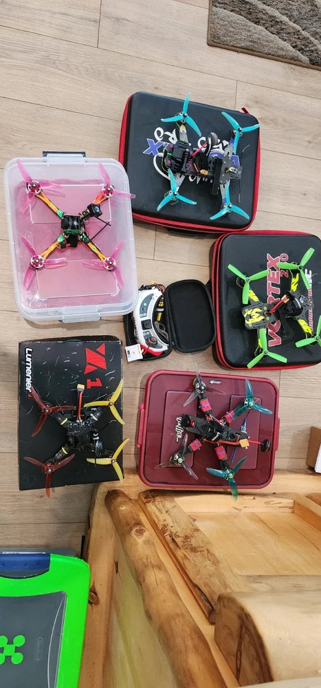 FPV drone set with colorful quadcopters in carrying cases and remote controller