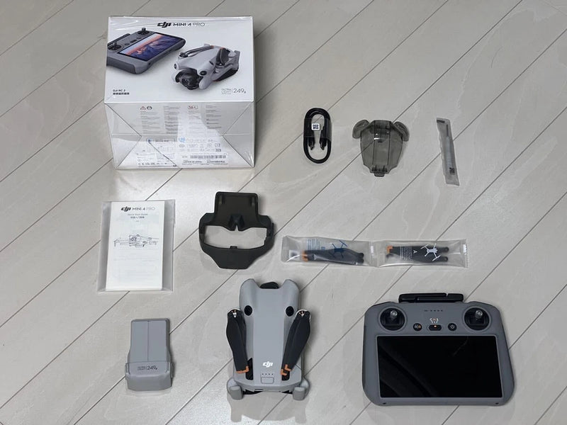 DJI Mini 4 Pro drone with DJI RC-2 controller and charging accessories laid out