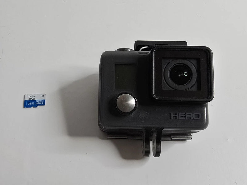 GoPro HERO action camera in black housing with lens and attached mount; 32GB SD card visible