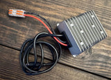 DC-DC voltage converter with silver ribbed metal case and attached red/black wires