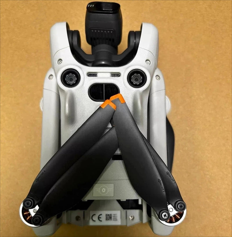 Folded white and black drone body with protective arms and front sensors