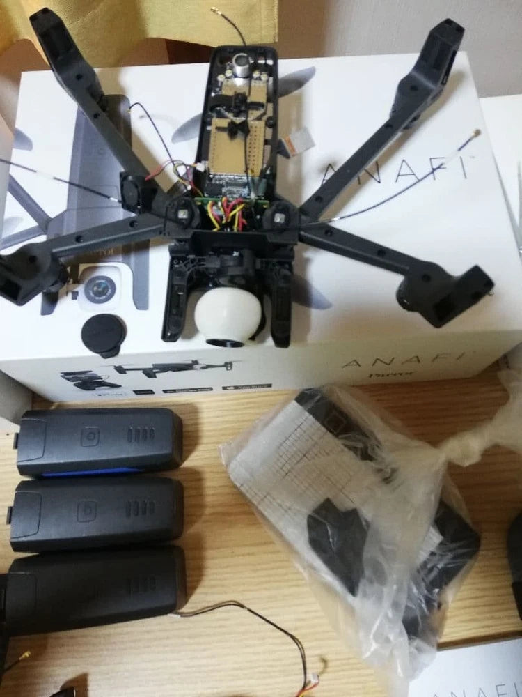 Disassembled drone parts lot with quad arms, body, and multiple black battery packs