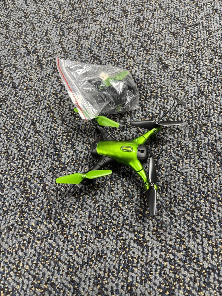 Green toy drone with four propellers, folded legs and black landing gear